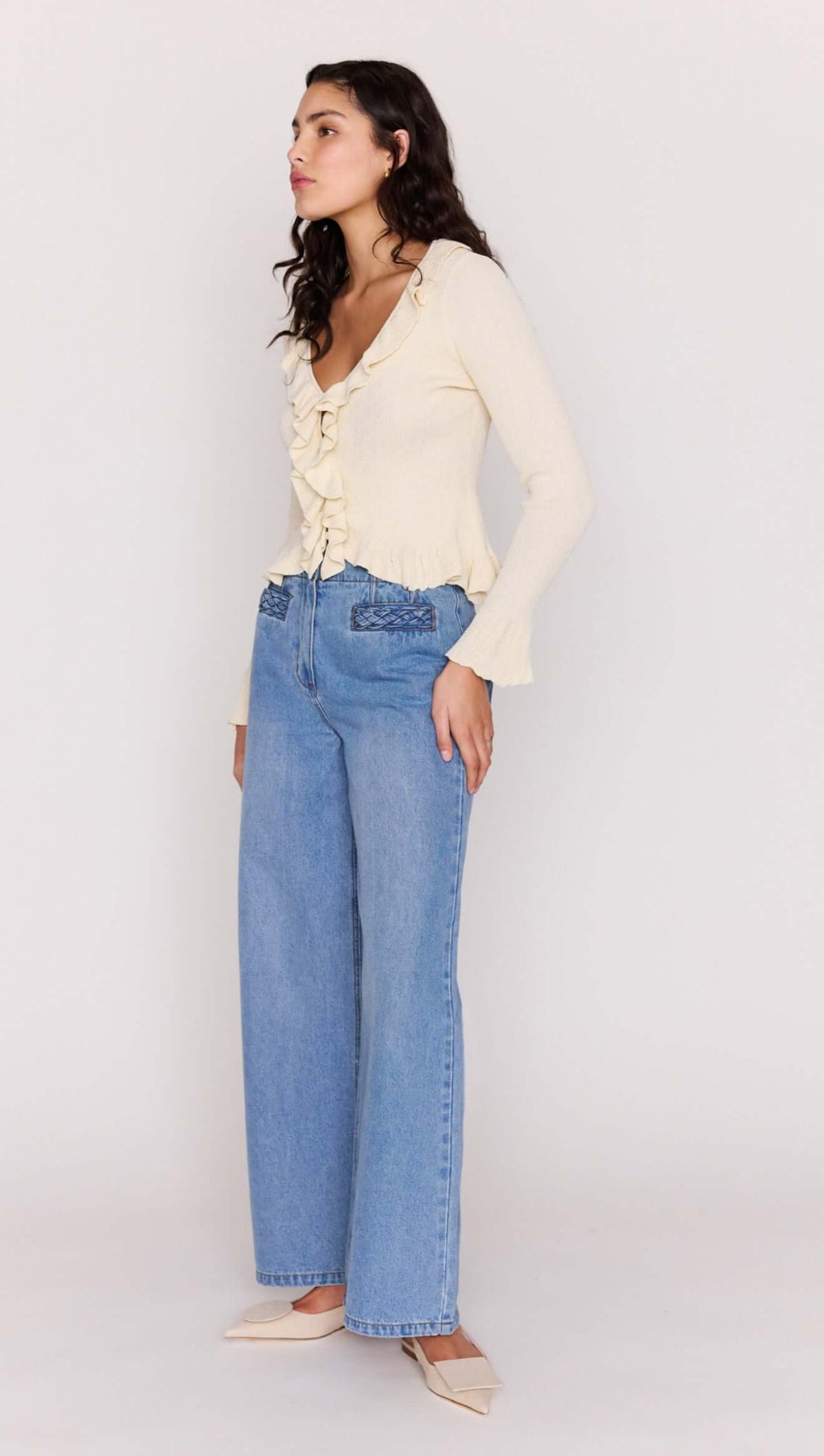 Model wearing a Cream Ruffled Cardigan with button-through front, paired with blue wide-leg jeans.