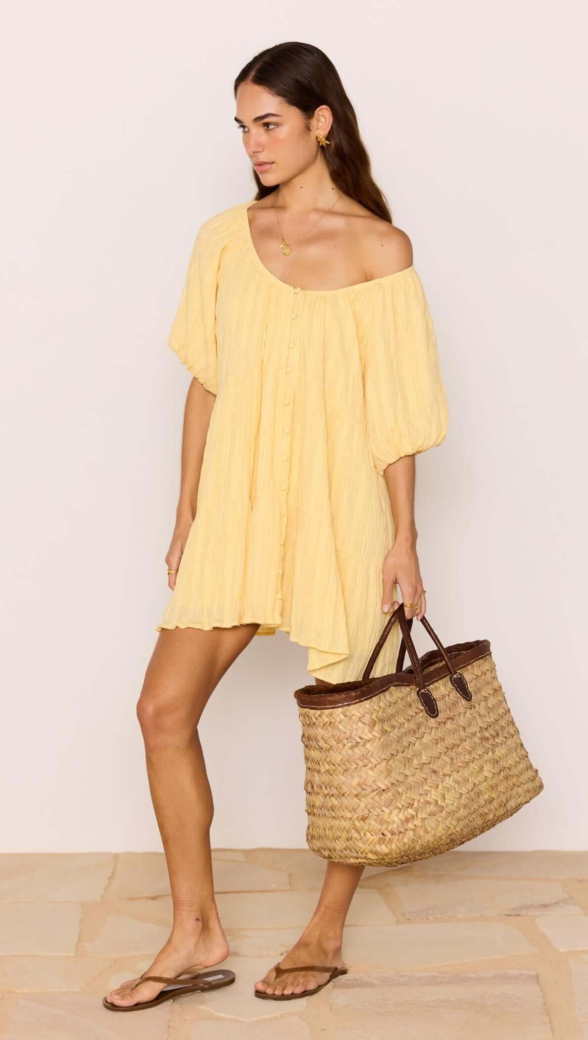 Relaxed Yellow Cotton Tiered Mini Dress worn with a woven bag, perfect for summer outings.