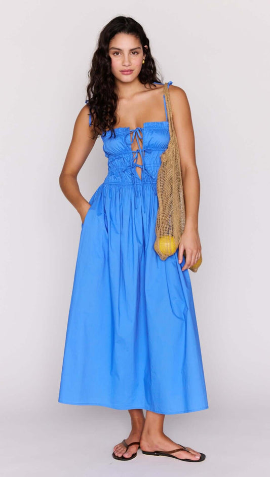 Model wearing a blue cotton tie detail midi dress with a shirred bodice and adjustable tie detailing.