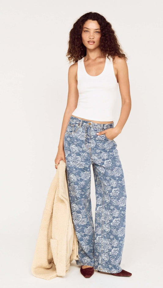 Woman wearing Mid Rise Floral Denim Wide Leg Jeans with a white tank top and beige jacket.