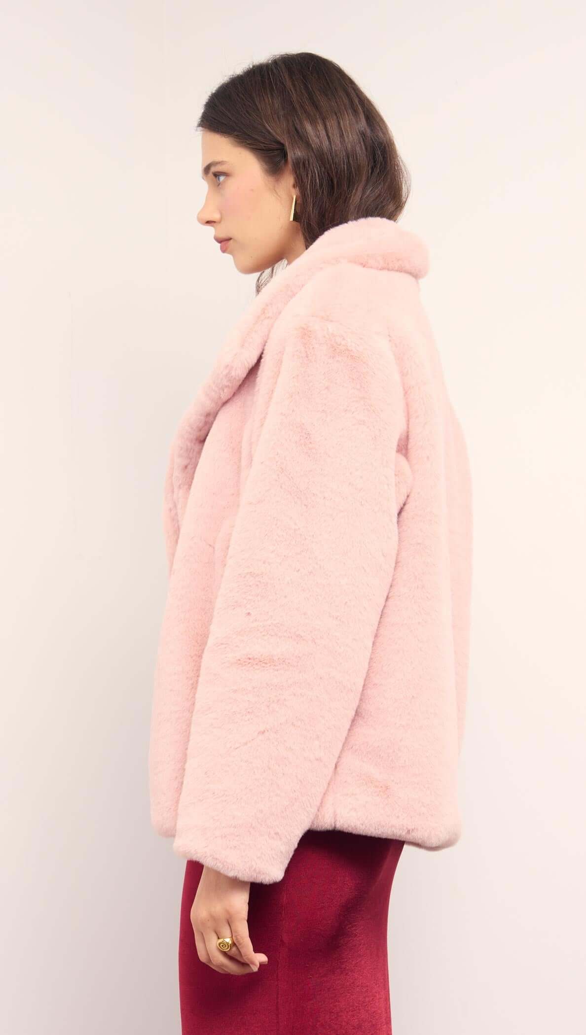 Side view of a model wearing the Dusty Pink Faux Fur Coat, showcasing its soft fur and relaxed silhouette.