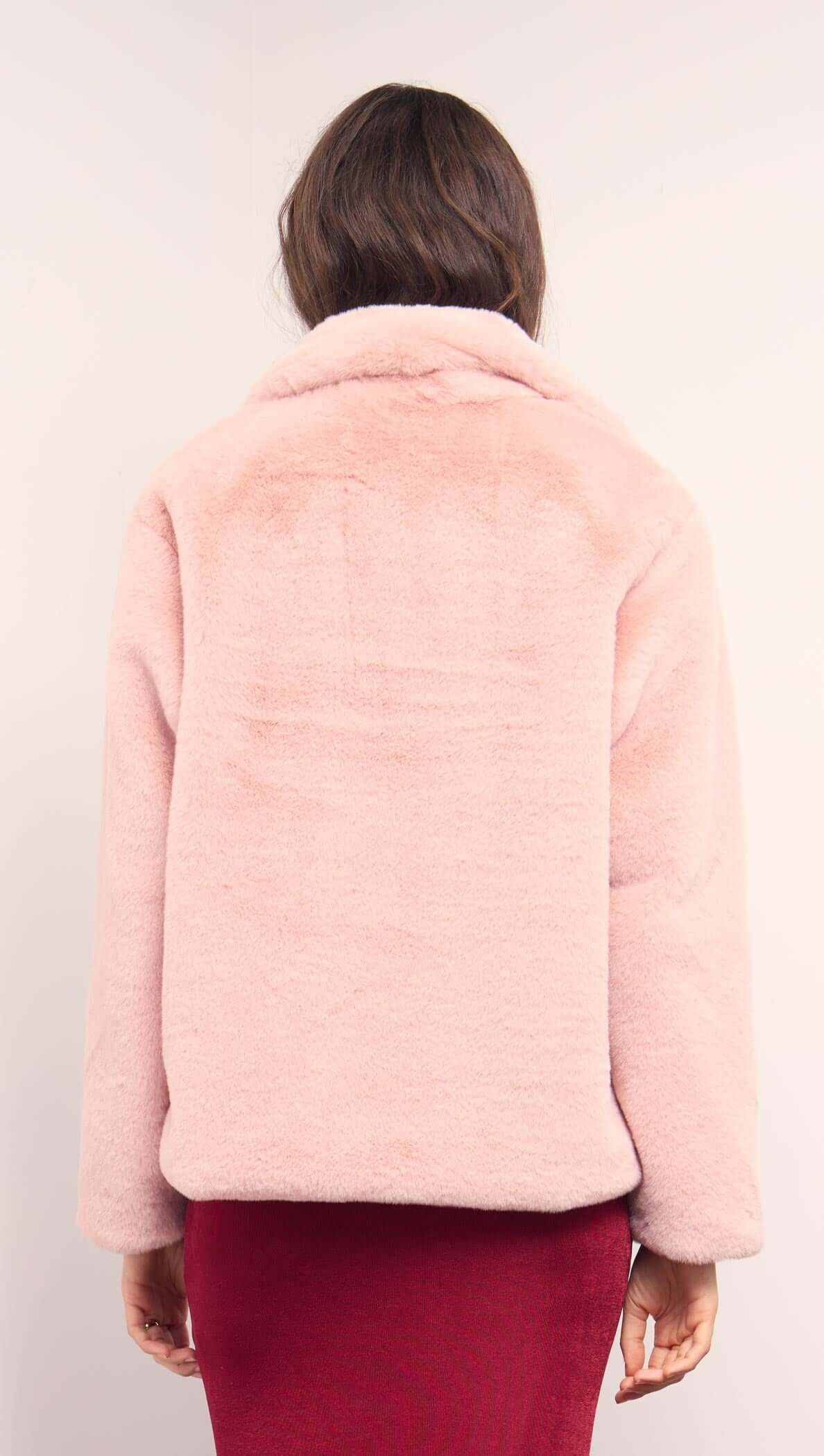 Back view of a woman wearing a Dusty Pink Faux Fur Coat, showcasing its plush texture and relaxed fit.