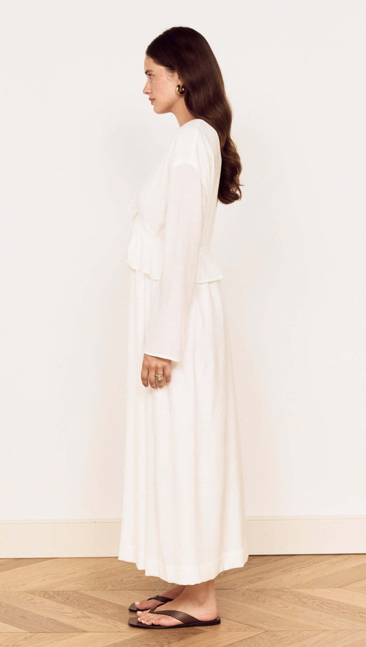Side view of a woman wearing a White Crinkle Tie Front Midi Dress with relaxed long sleeves and a layered peplum.