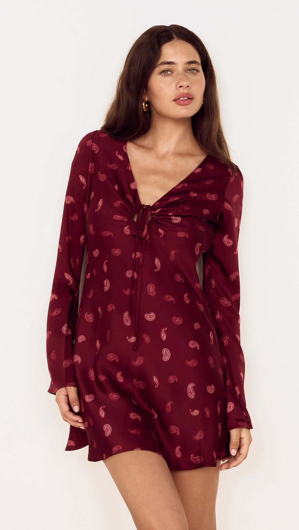 Model wearing the Wine Satin Paisley Knot Front Bias Mini Dress featuring a V-neckline and flared sleeves.