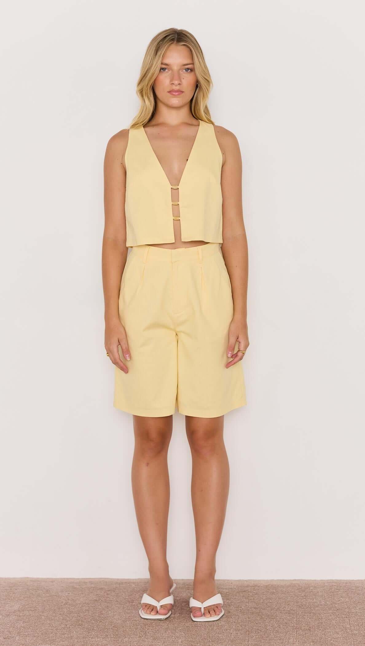 Model wearing a Butter Yellow High-Waist Bermuda Short paired with a matching sleeveless top, perfect for summer outfits.