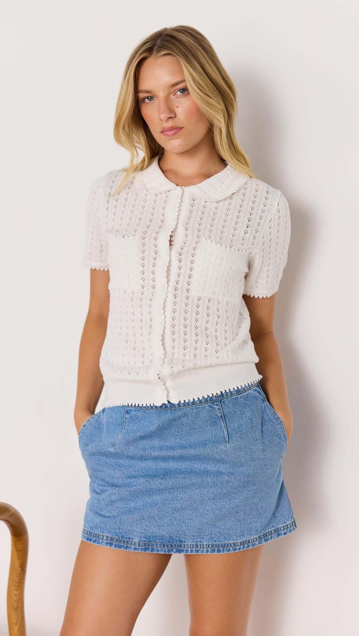Model wearing a white French Pointelle short sleeve knit top, paired with a denim skirt, showcasing a casual summer look.