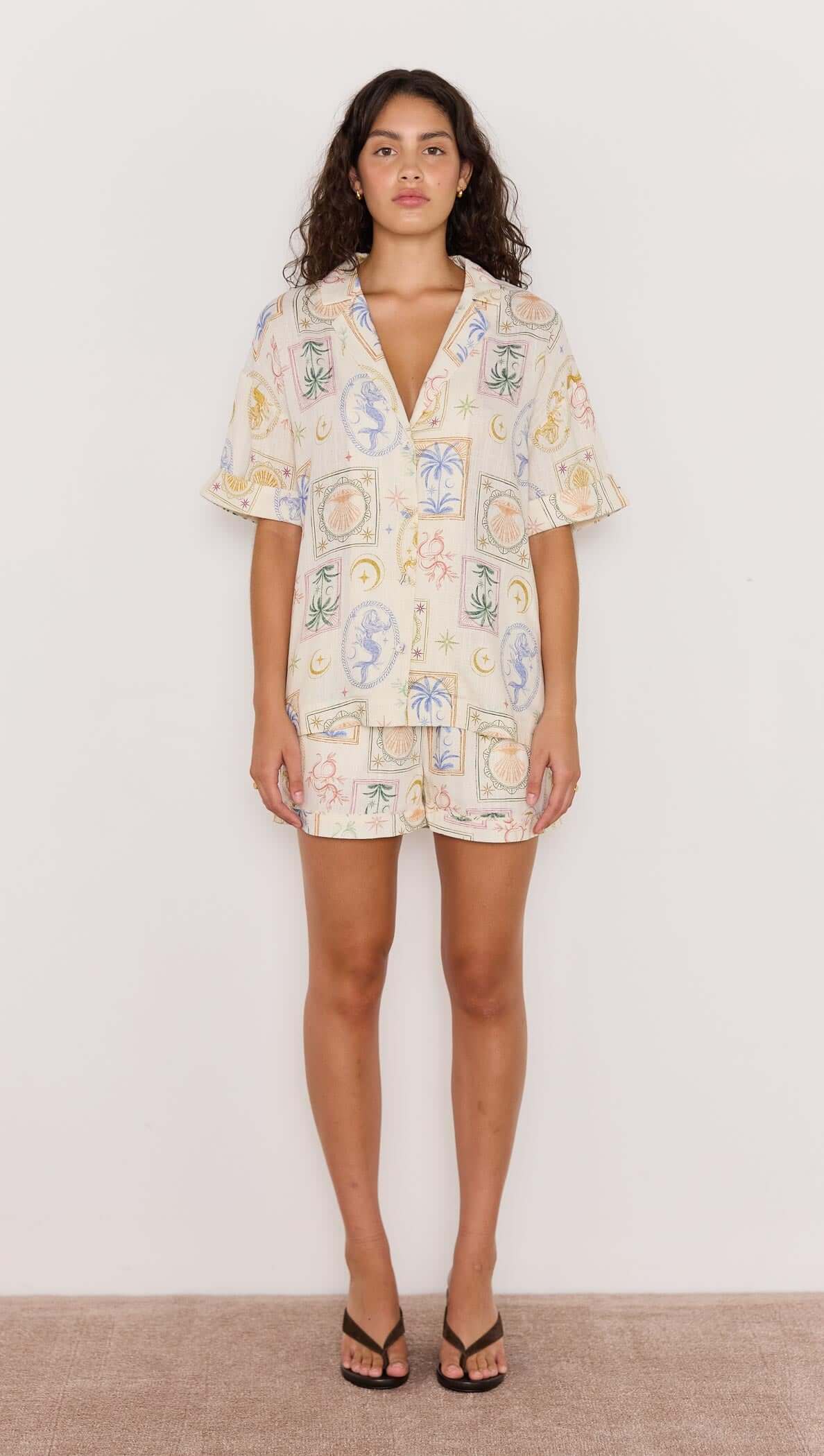 Model wearing a printed linen blend loose resort shirt with pastel coastal motifs and a relaxed fit.