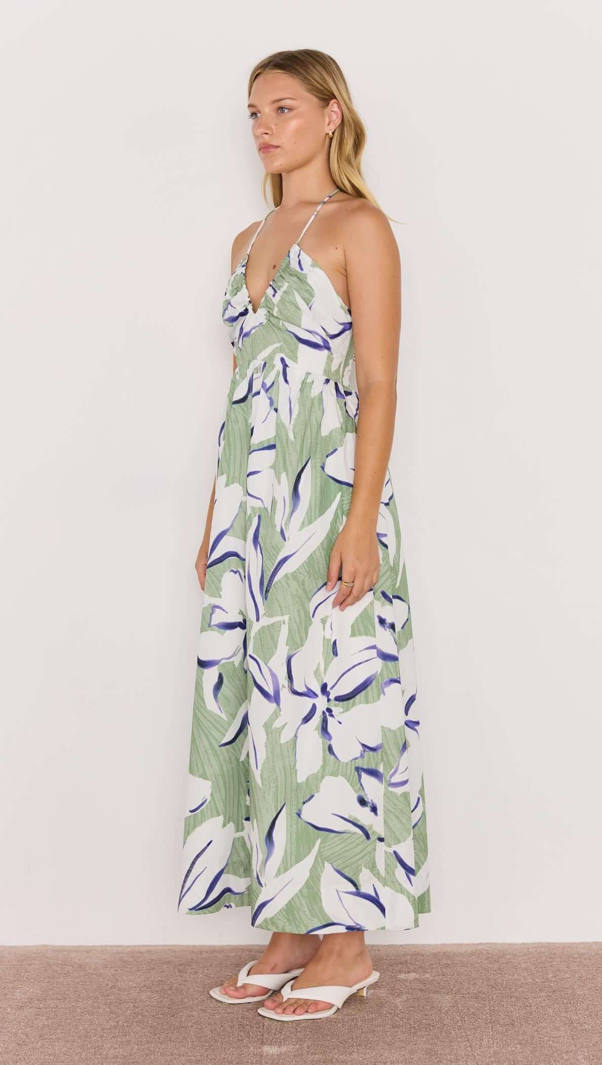Model wearing a green and white floral halter-neck midi dress, showcasing a relaxed fit and vibrant floral print.