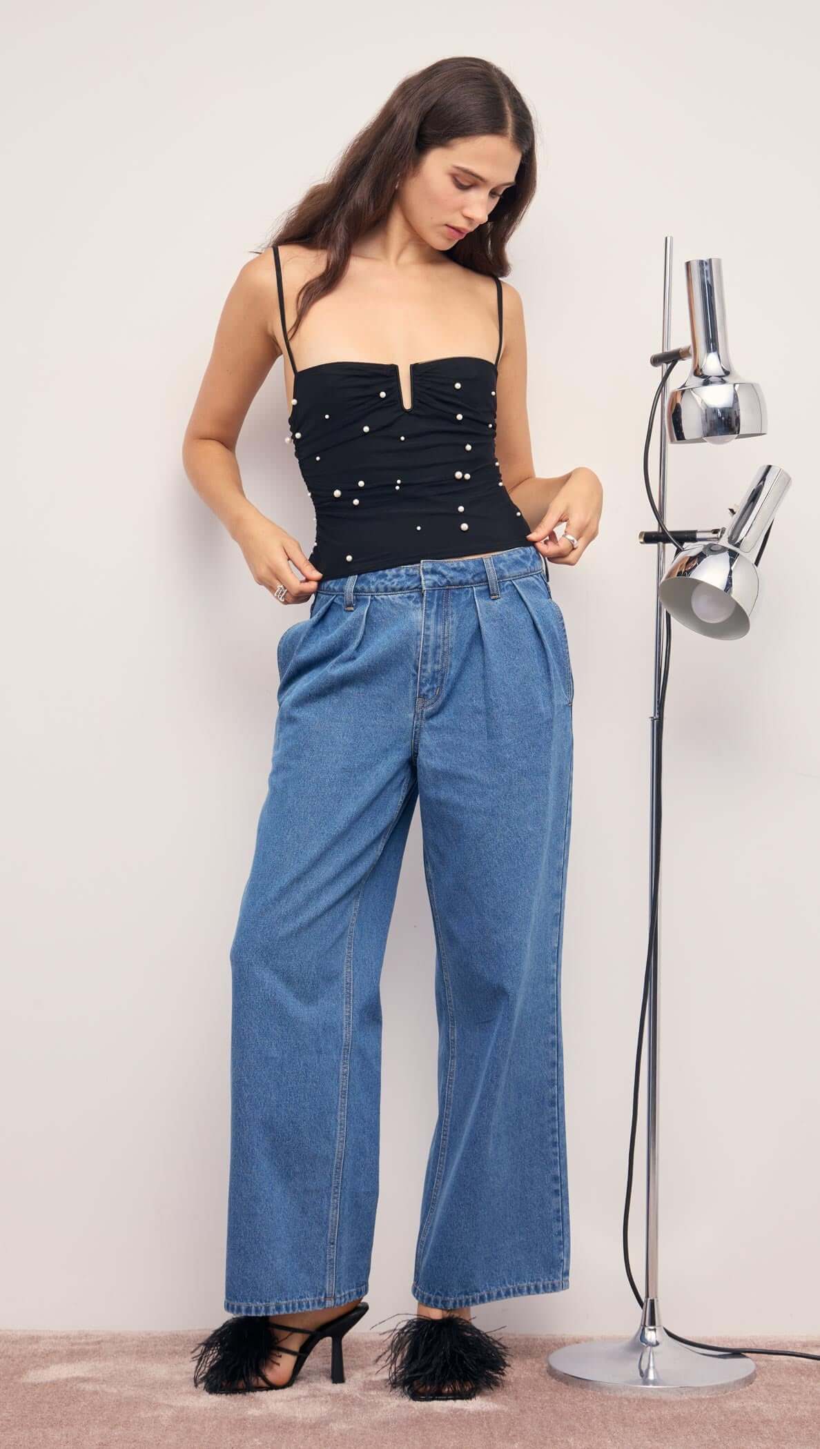 Woman wearing a Pearl Embellished Black Mesh Crop Top with denim pants and stylish heels.