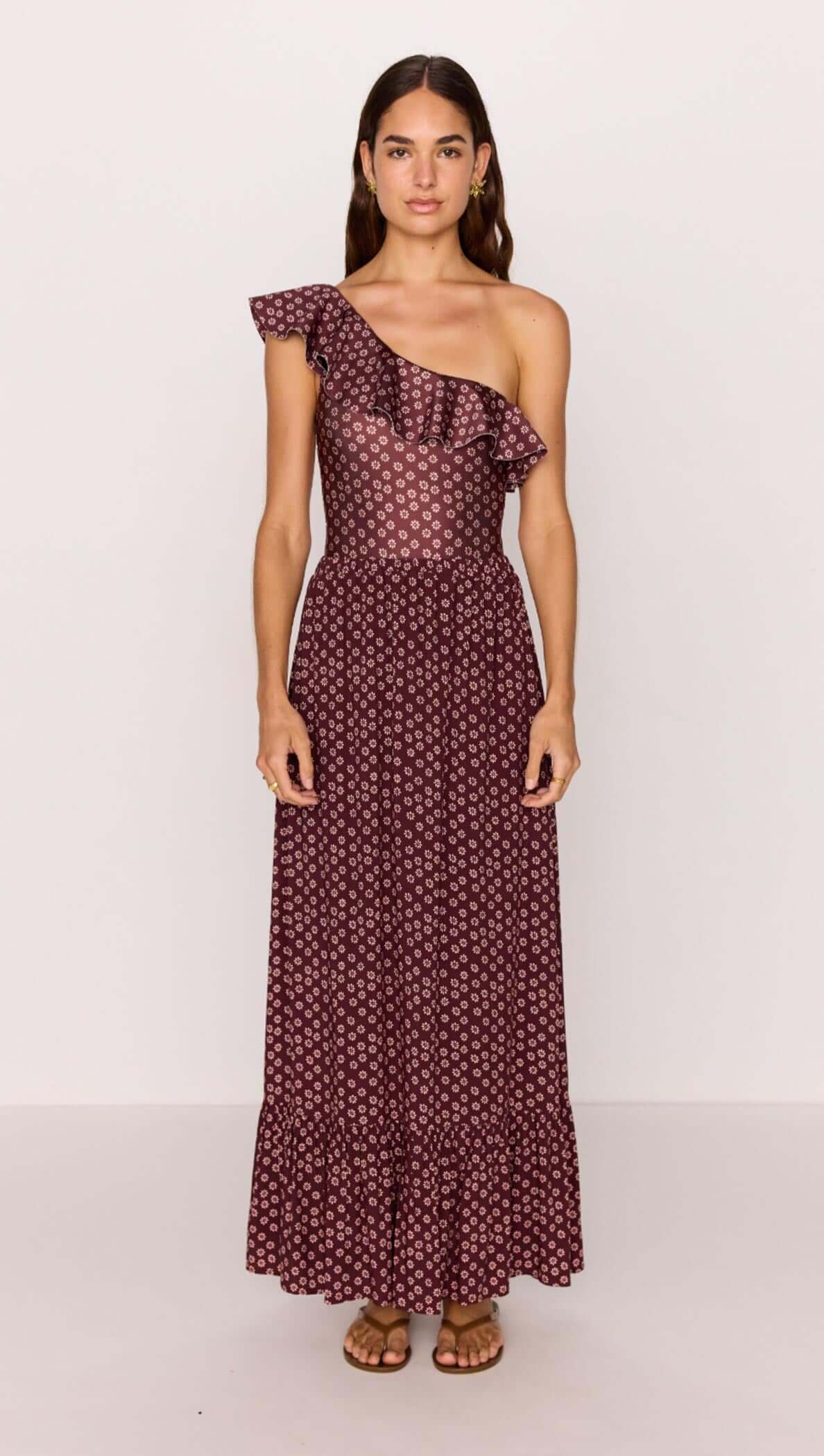 Model wearing a burgundy floral print ruffle hem maxi skirt, showcasing a stylish, one-shoulder design.
