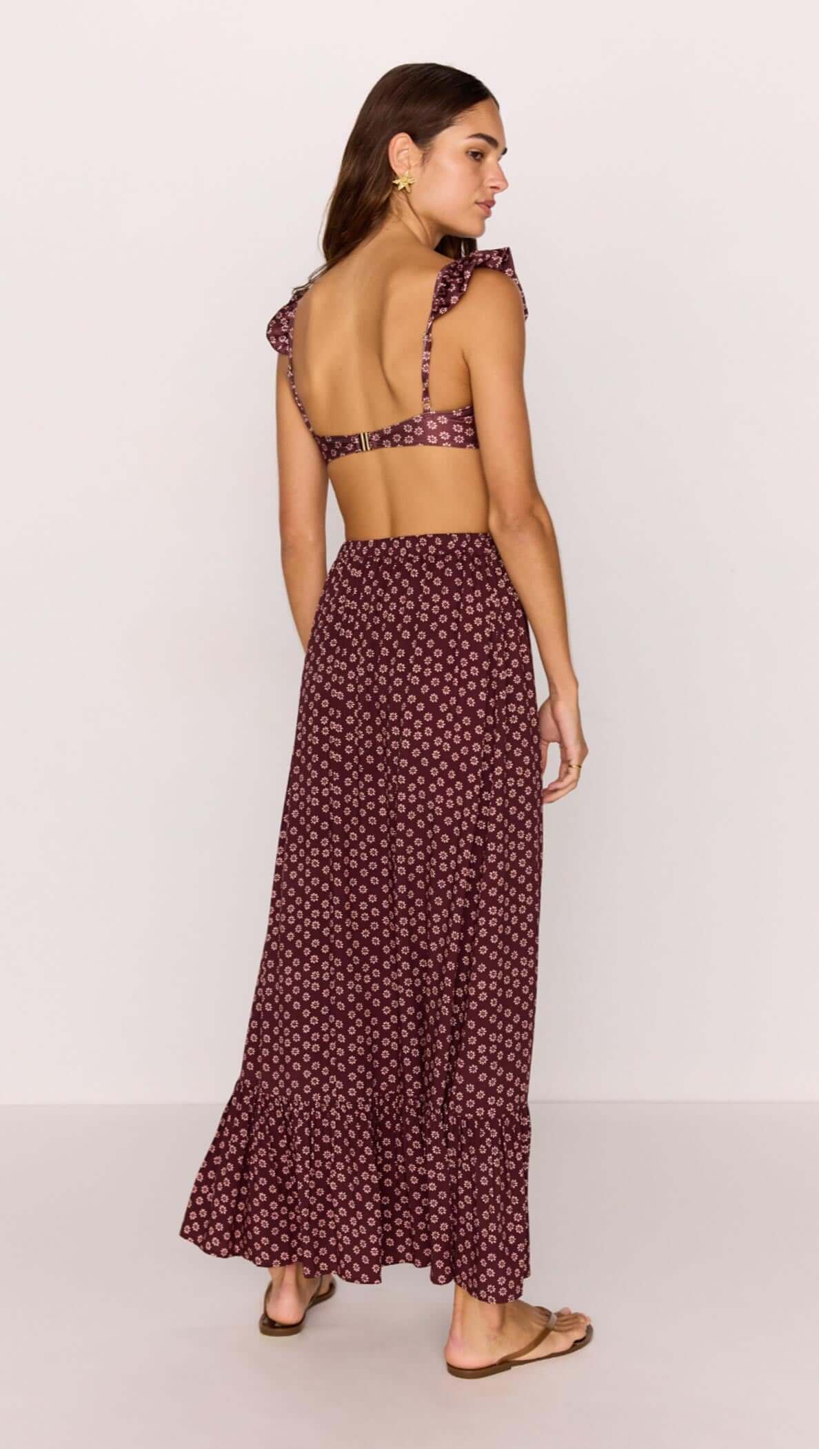 Model wearing a burgundy floral print maxi skirt with a ruffle hem and matching top, showcasing a stylish summer look.