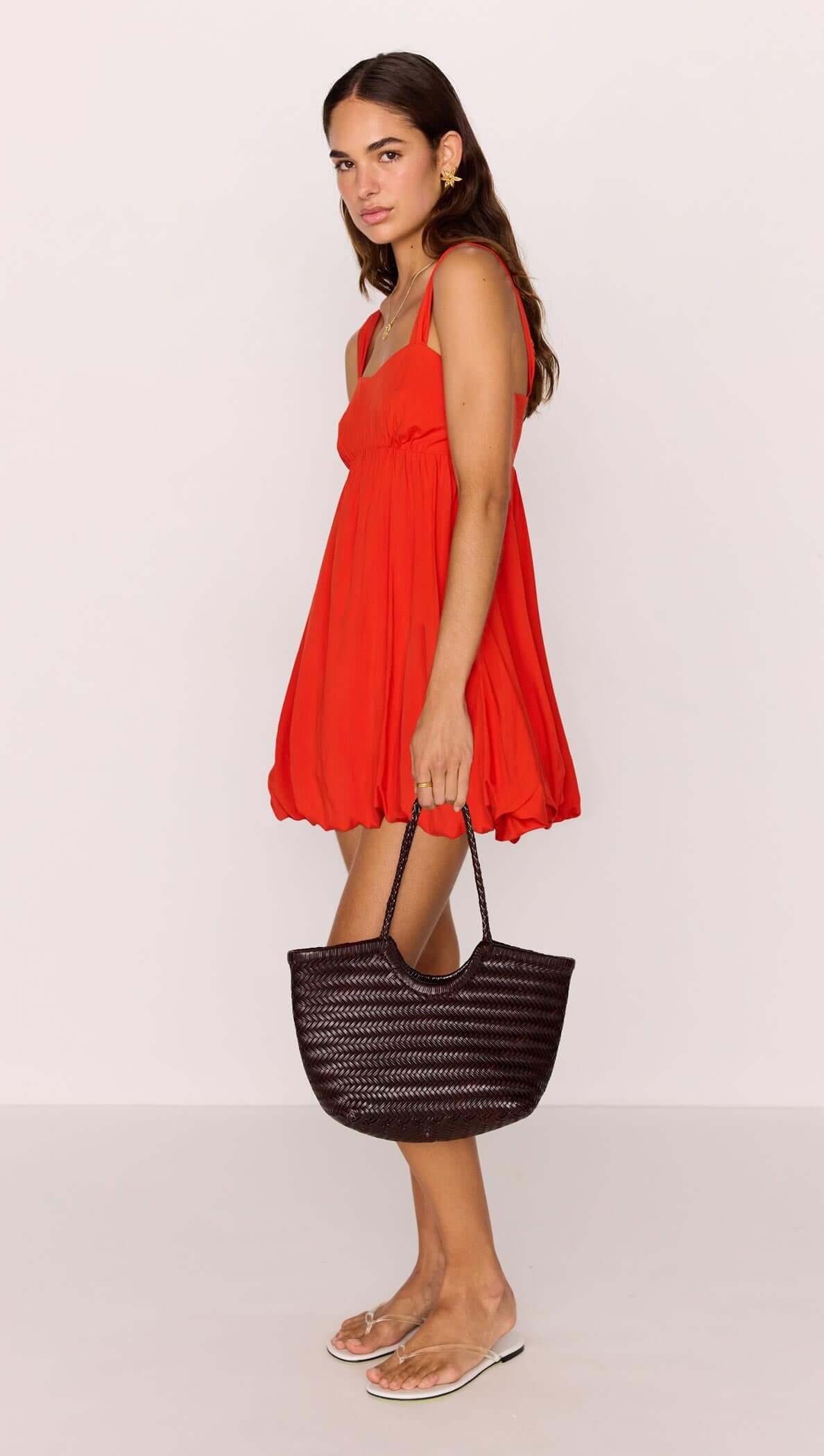 Model wearing a Scarlett Red Bubble Mini Dress with a black woven bag and stylish sandals.