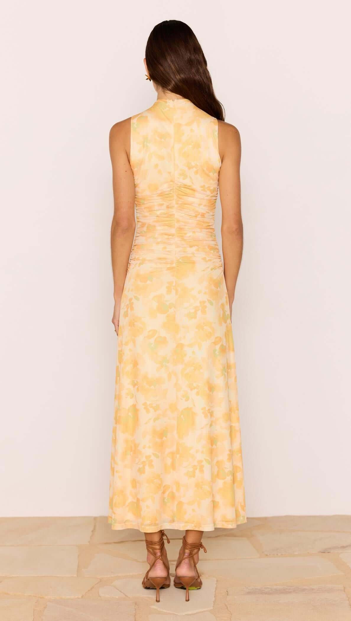 Back view of a woman wearing a Yellow Floral Mesh Midi Dress showcasing a soft floral pattern and fitted bodice.