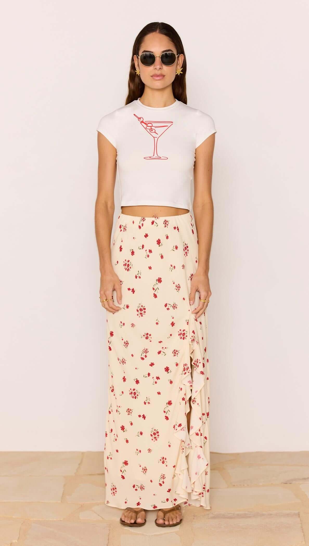 Model in sunglasses wearing Red & Cream Floral Ruffle Bias Maxi Skirt with a white cropped top.
