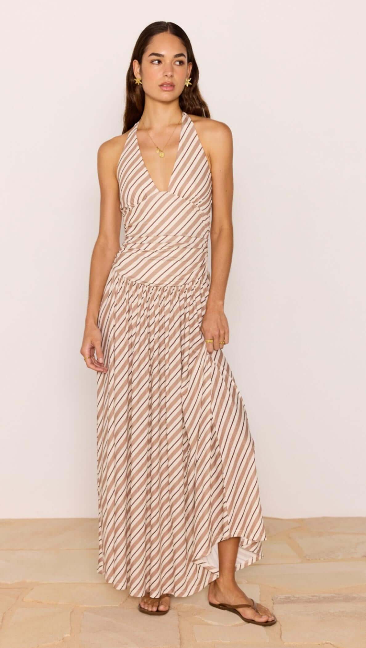Brown & Cream Stripe Low-Waist Halter Maxi Dress worn by model, showcasing its flowing design and plunging neckline.
