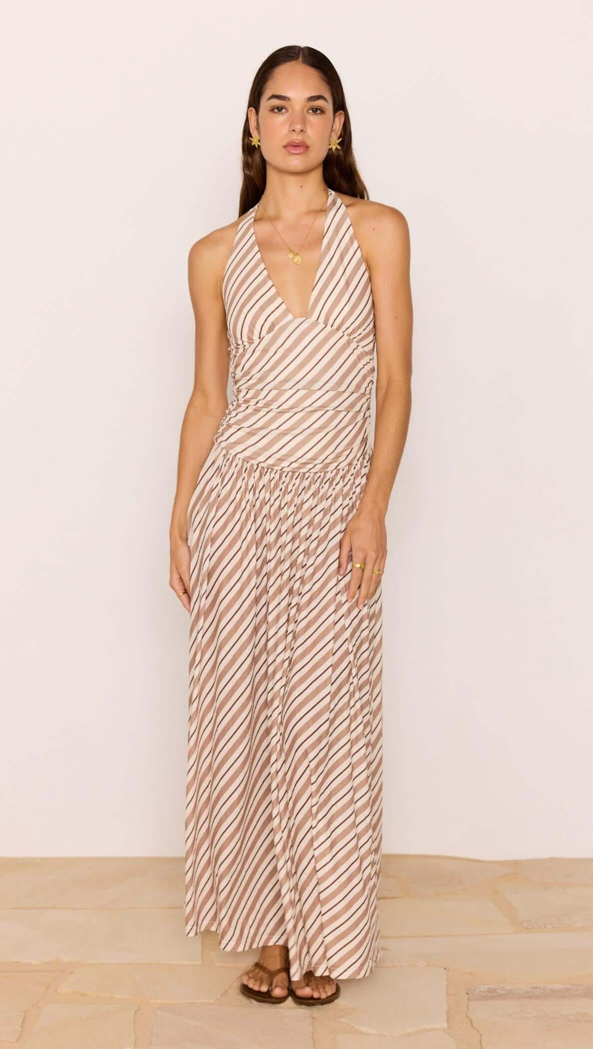 Brown & Cream Stripe Low-Waist Halter Maxi Dress worn by model, featuring plunging neckline and flowy skirt.