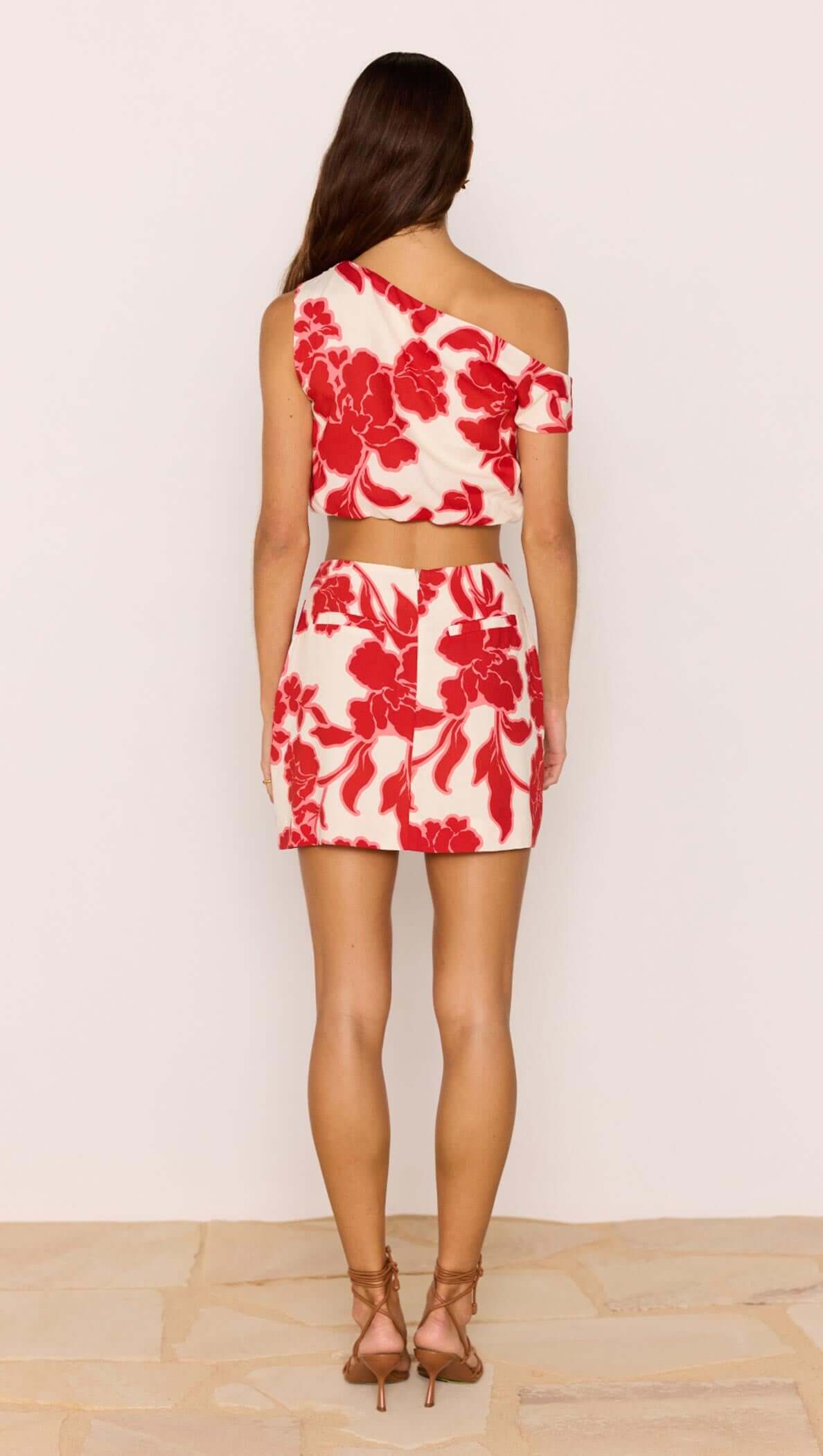 Red & White Floral Linen Blend Asymmetric Crop Top worn with matching mini skirt, showcasing a back view and floral design.