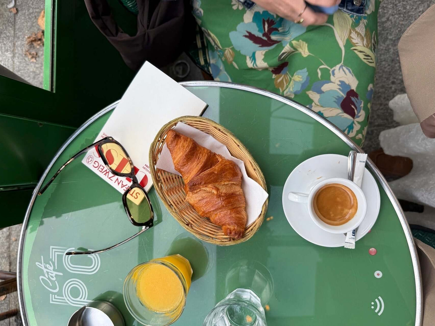 72 hours in Paris travel guide with breakfast at a cafe, featuring croissant and coffee on a green table.
