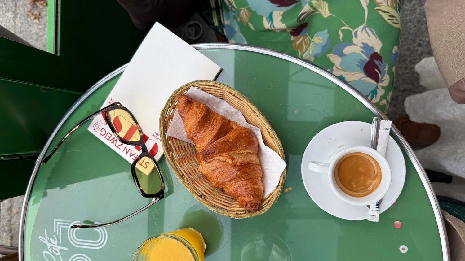 72 hours in Paris travel guide with breakfast at a cafe, featuring croissant and coffee on a green table.