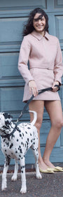 Model wearing Audrey Herringbone Jacket with a cropped silhouette, walking a Dalmatian dog against a garage door.
