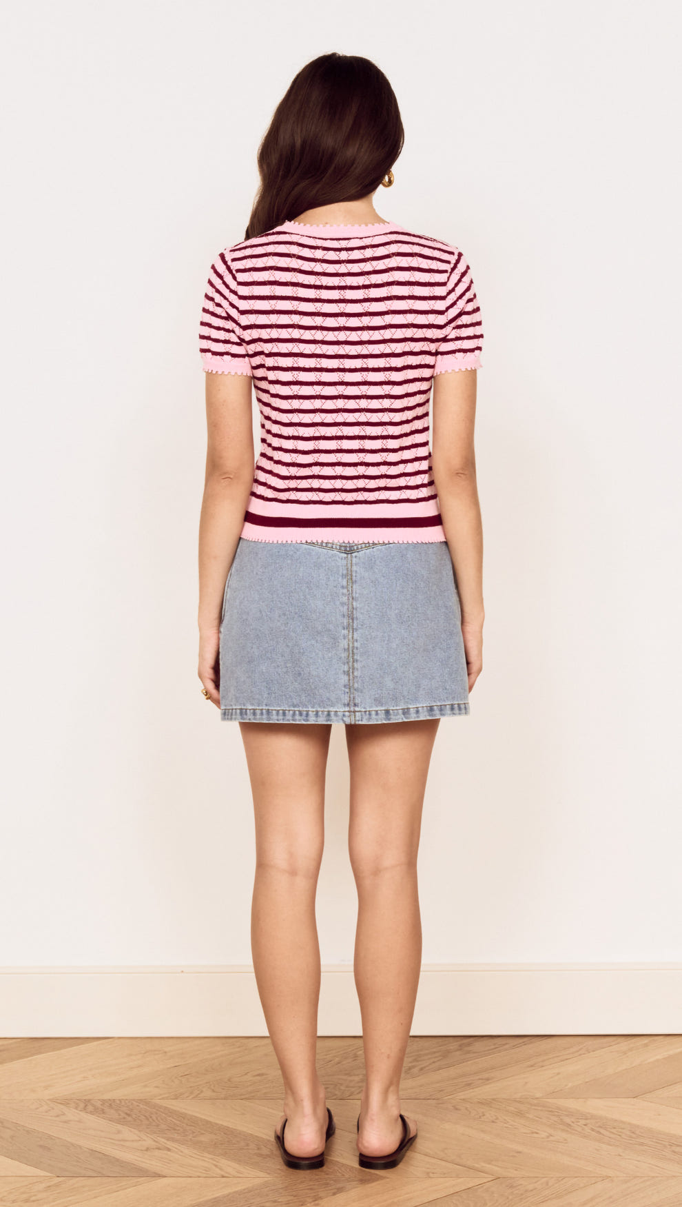 Back view of a model wearing a Pink Stripe Pointelle Knit Tee paired with a denim skirt.