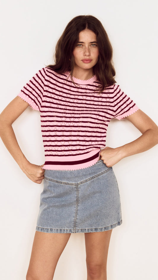 Model wearing a Pink Stripe Pointelle Knit Tee with openwork knit and horizontal stripes, styled with a denim skirt.