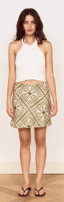 Model wearing Scarf Print Bias Mini Skirt in Olive with a white crop top and flip flops.