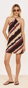Model wearing Halter Mini Dress in Abstract Stripe featuring a bold diagonal stripe print in chocolate and burgundy.