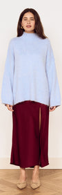 Model wearing a light blue sweater paired with a Burgundy Side Split Bias Midi Skirt, showcasing elegant style and comfortable fashion.