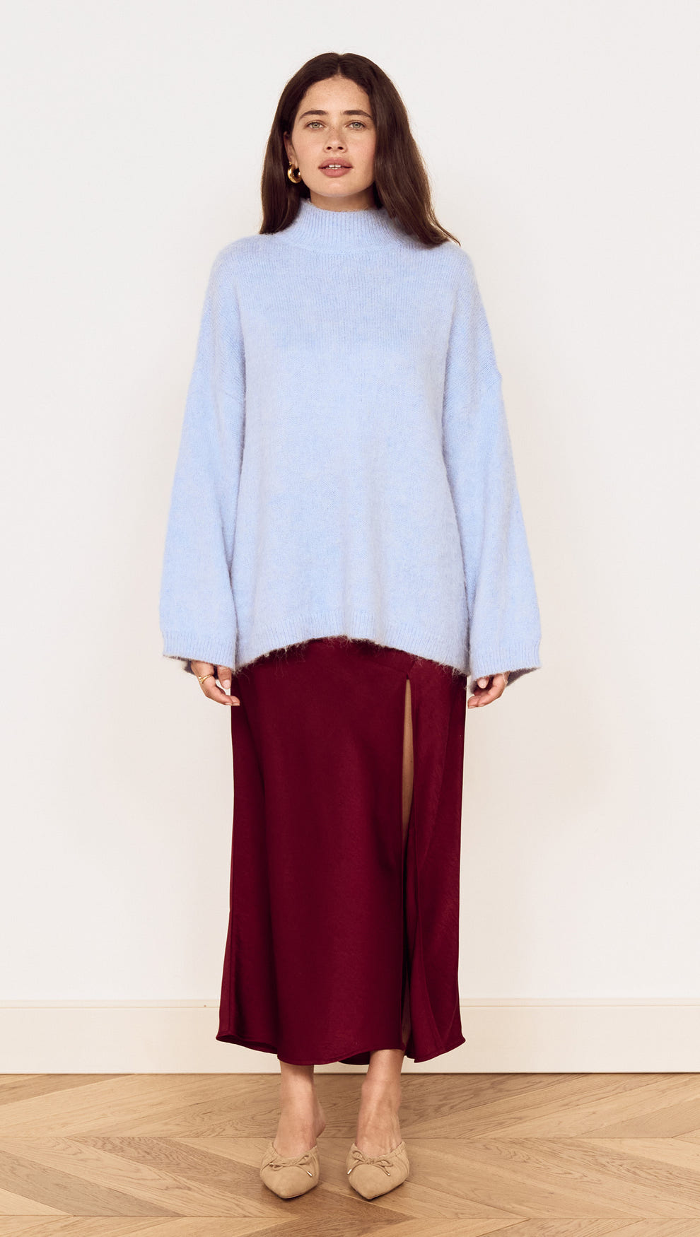 Model wearing a light blue sweater paired with a Burgundy Side Split Bias Midi Skirt, showcasing elegant style and comfortable fashion.