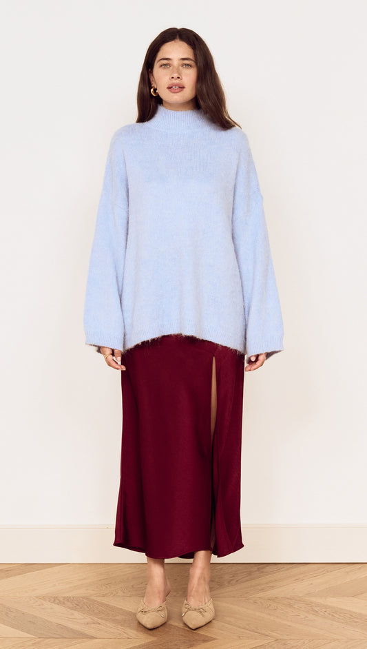 Model wearing a light blue sweater paired with a Burgundy Side Split Bias Midi Skirt, showcasing elegant style and comfortable fashion.