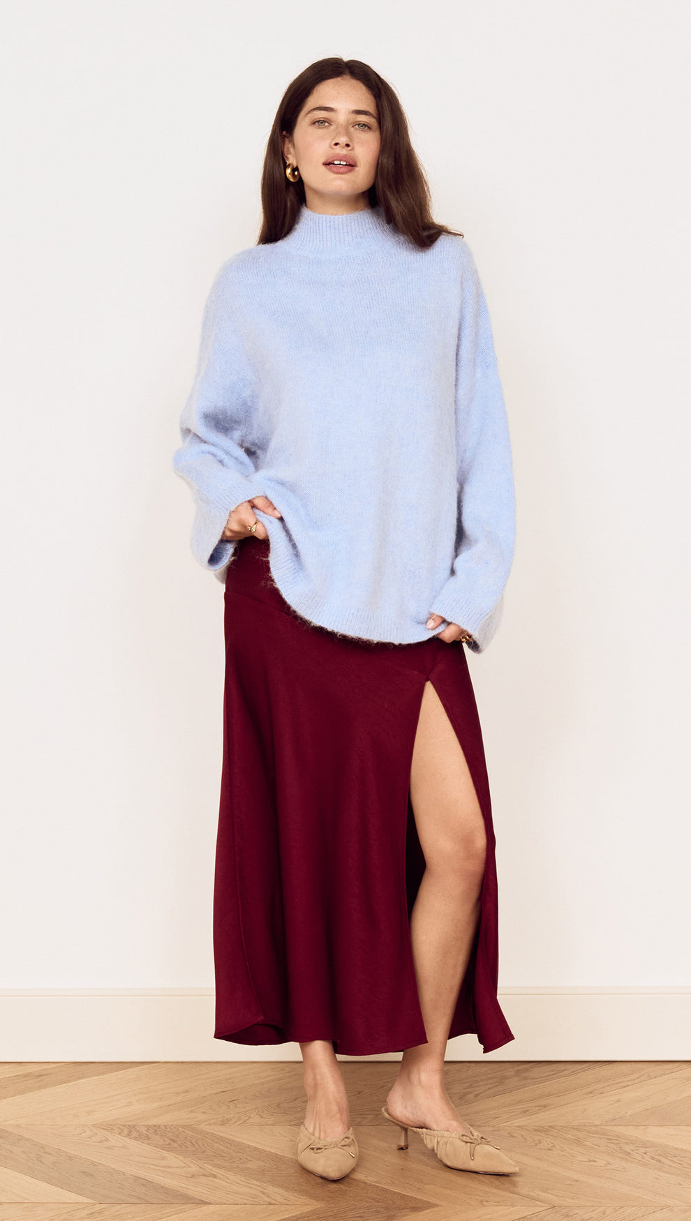 Model wearing a Burgundy Side Split Bias Midi Skirt with a light blue top, showcasing the skirt's elegant split design.