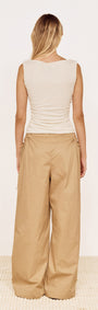 Back view of a model wearing a Boat Neck Rib Detail Mesh Top in Cream paired with wide beige trousers.