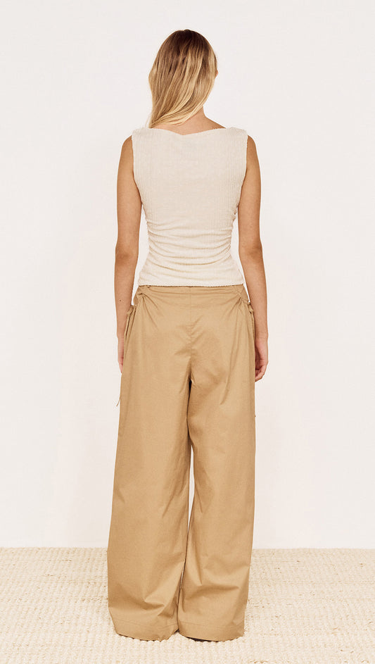 Back view of a model wearing a Boat Neck Rib Detail Mesh Top in Cream paired with wide beige trousers.