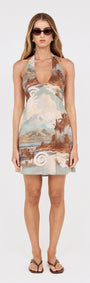 Island Print Halterneck Mini Dress featured on a model wearing sunglasses and flip-flops, showcasing a scenic print.