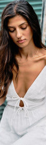 Model wearing Cotton Broderie Anglaise Sleeveless Dress with a plunging V-neckline, holding a flower.