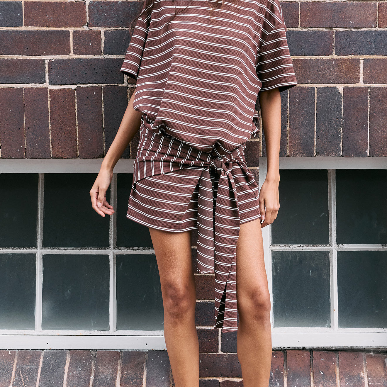 Model wearing a Striped Tie Waist Jersey Mini Dress with chocolate stripe print, featuring a relaxed style and adjustable tie at the waist.