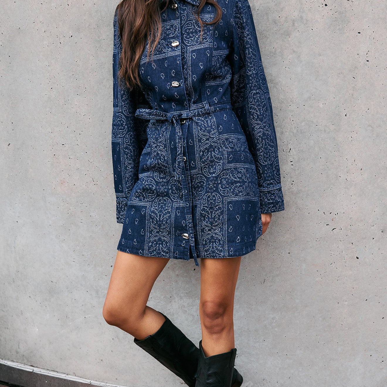 Model wearing a Paisley Jacquard Denim Shirt Dress with a collared neckline and waist tie, styled with knee-high boots.
