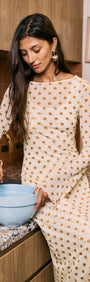 Butter Yellow Polka Dot Midi Dress worn by a woman mixing ingredients in a kitchen with a blue bowl.