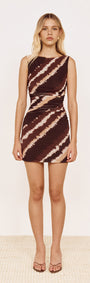 Model wearing a fitted Mesh Mini Dress in Abstract Stripe with chocolate and neutral tones, showcasing boat neckline and ruching.
