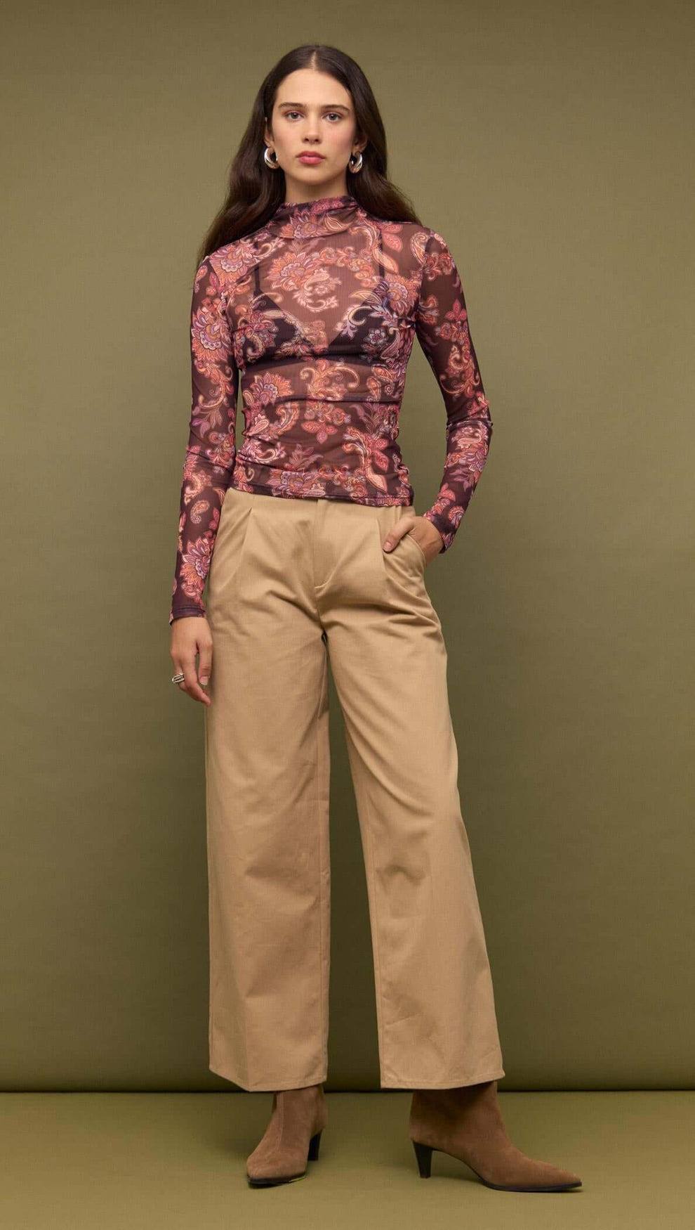 Model wearing a Sheer Printed Long Sleeve Mesh Top with patterned fabric and high neckline, styled with wide-leg pants.