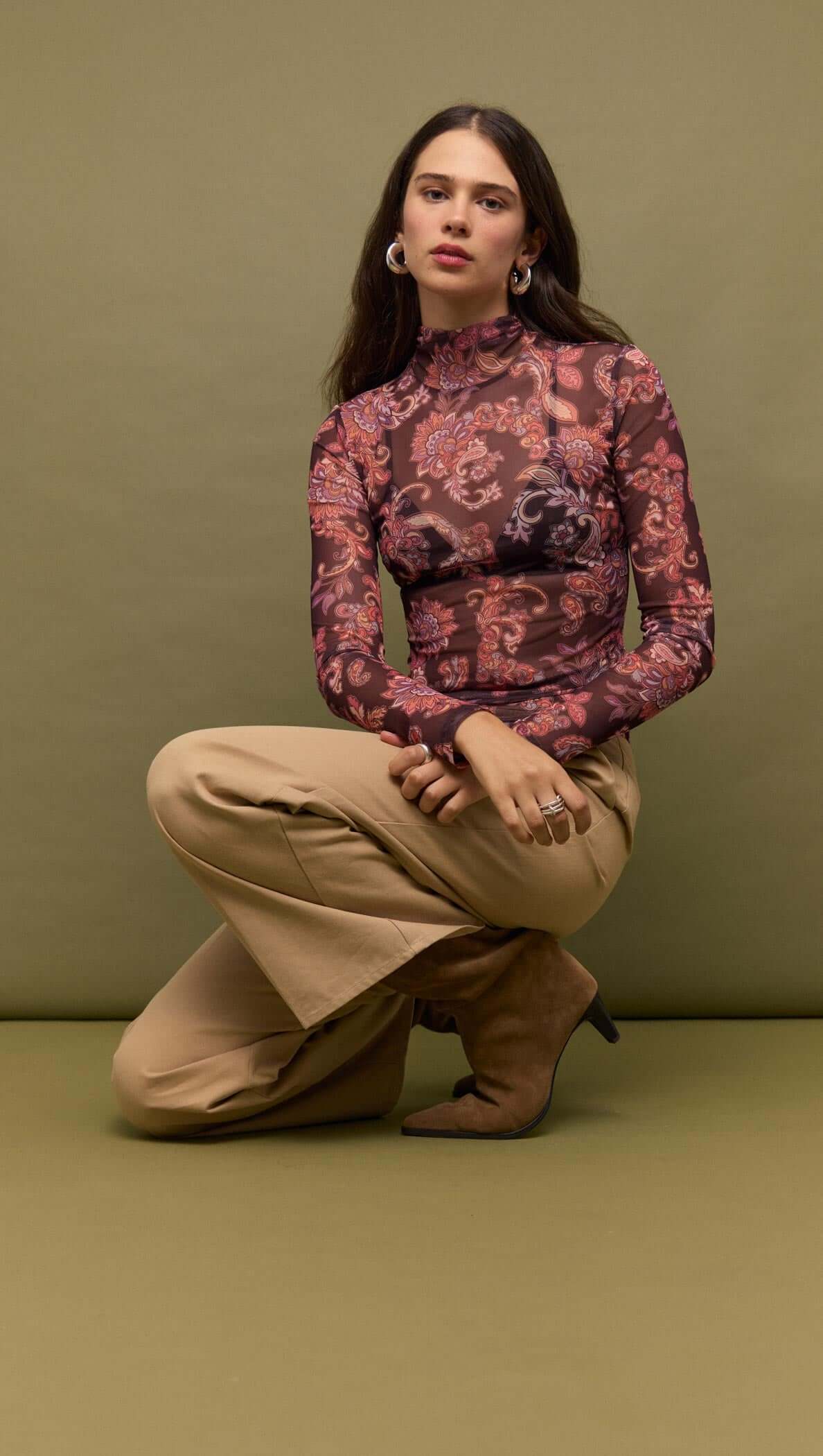 Model wearing Sheer Printed Long Sleeve Mesh Top with fitted silhouette on green background.