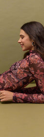 Model wearing Sheer Printed Long Sleeve Mesh Top in a floral print, styled on a green background.
