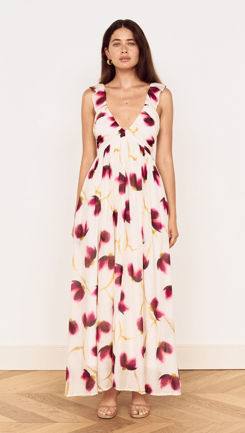 A model showcasing a Floral Ruffle Detail Bias Maxi Dress with a floral print in berry and golden tones.