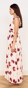 Model wearing a Floral Ruffle Detail Bias Maxi Dress showcasing a side view with a floral design in berry and gold tones.