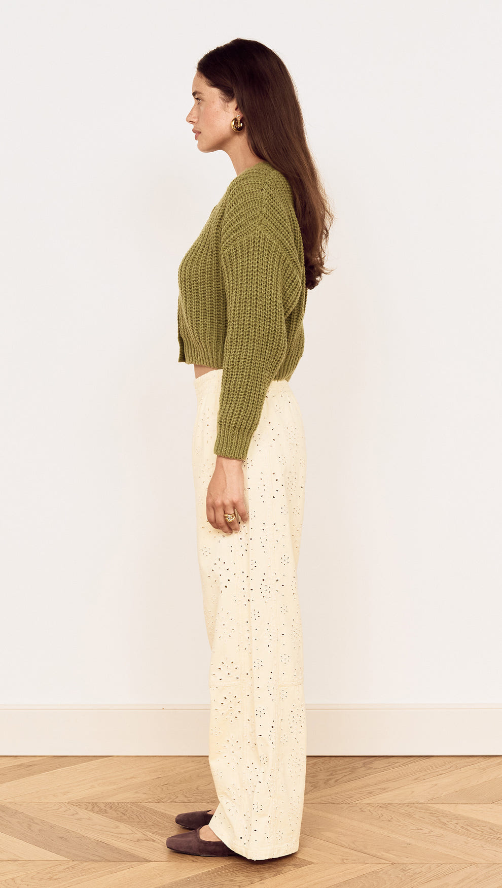 Side view of a model wearing a Green Cable Knit Cropped Cardigan paired with light-colored wide-leg pants.
