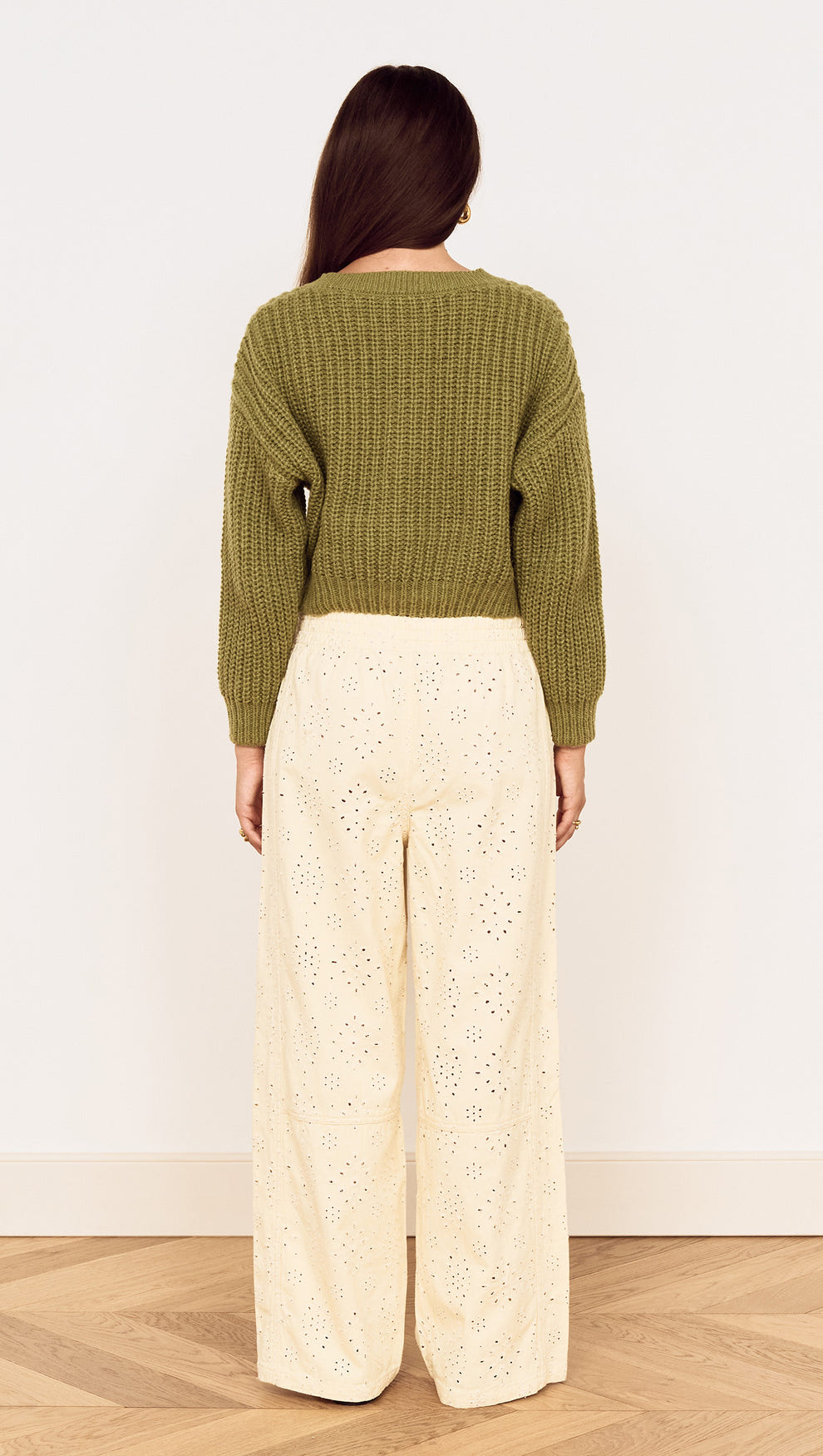 Back view of a model wearing a Green Cable Knit Cropped Cardigan with cream wide-legged pants.
