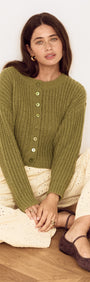 Woman wearing a Green Cable Knit Cropped Cardigan with button-front closure, styled with cream trousers.
