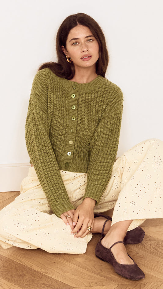 Woman wearing a Green Cable Knit Cropped Cardigan with button-front closure, styled with cream trousers.