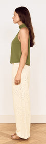Model in a side view wearing a Green High Neck Jersey Top paired with white wide-leg trousers.